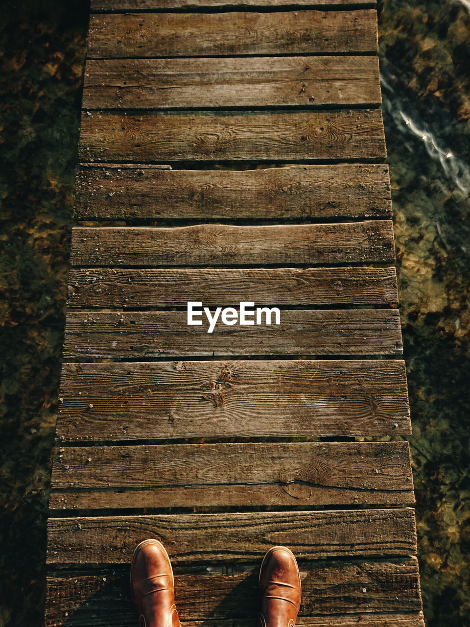 Low section of man standing on wooden plank