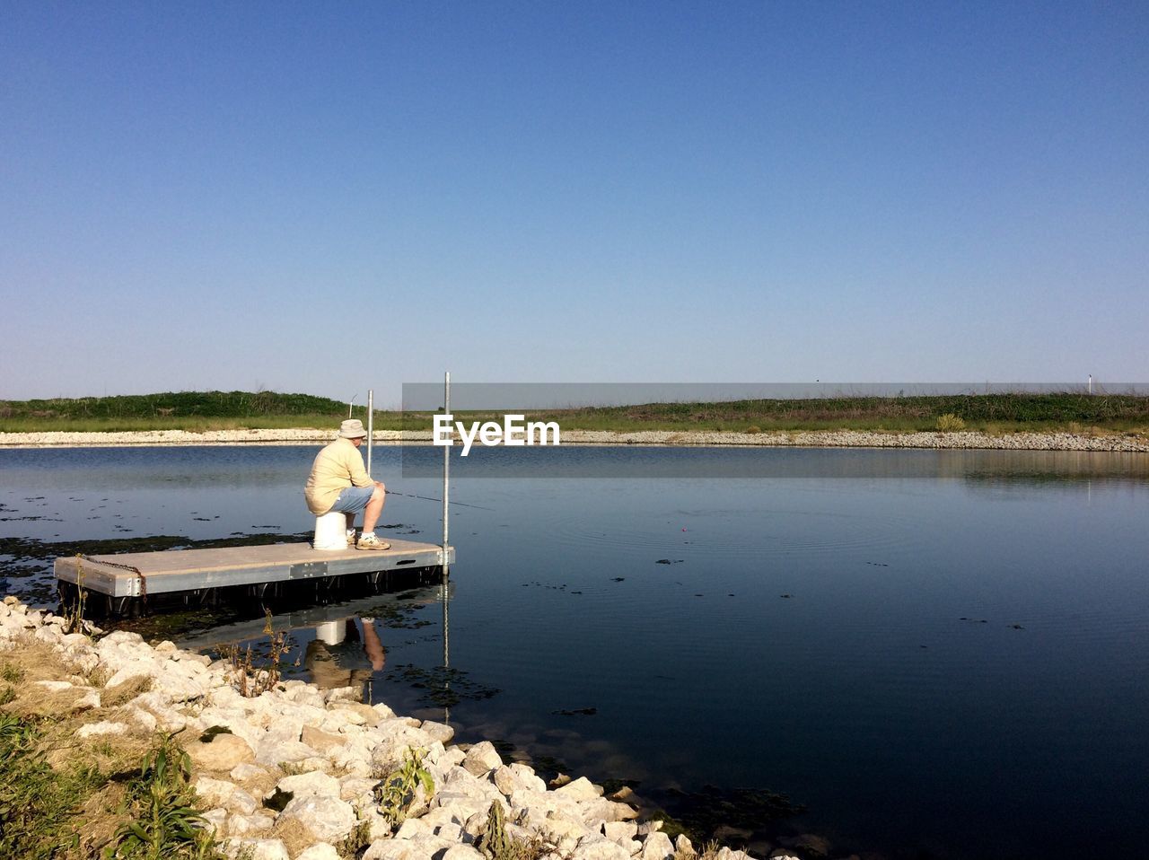 Man fishing on lake against clear sky