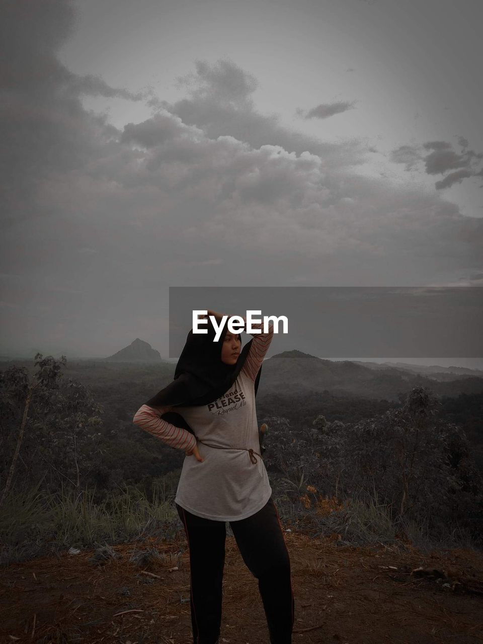 Teenage girl standing on mountain against sky