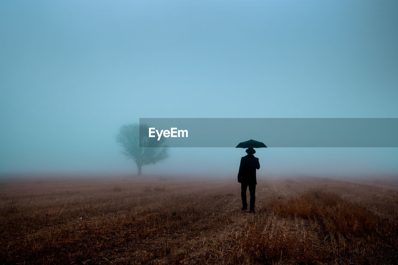 Man walking with an umbrella in fog