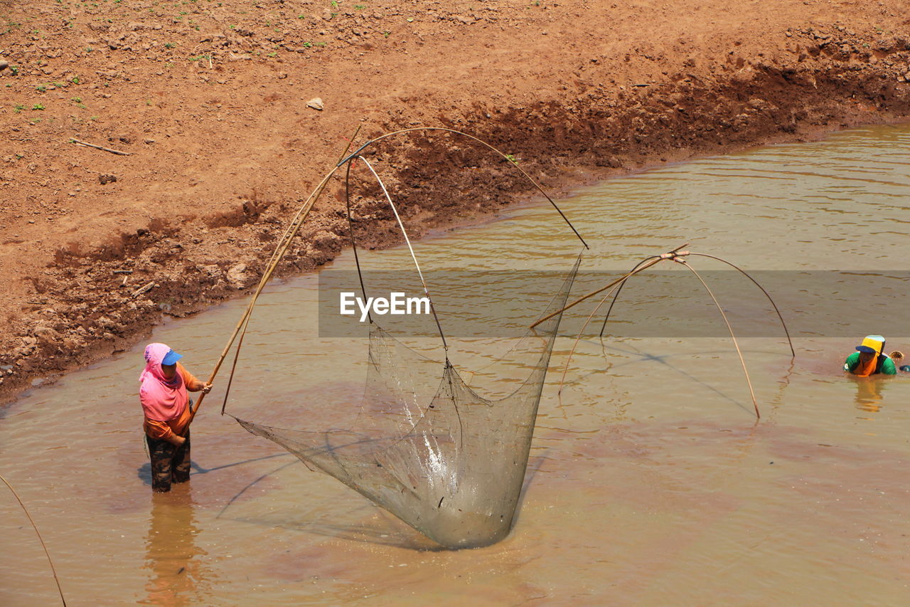 water, occupation, nature, men, working, high angle view, land, one person, sand, fishing, full length, adult, day, fishing net, activity, cleaning, outdoors, soil, lifestyles, fisherman, environment, agriculture, beach, hat