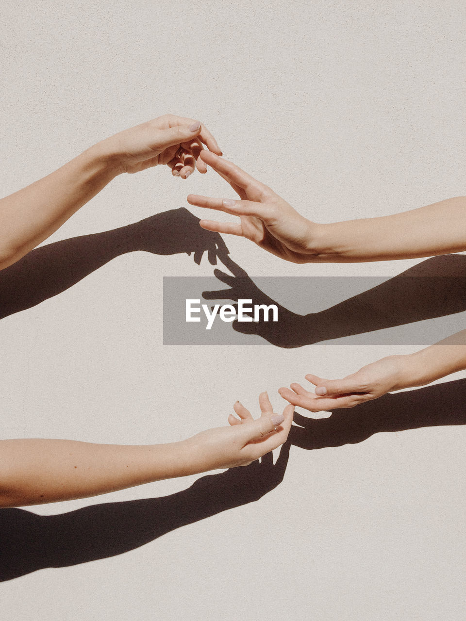 Cropped hands of women against gray wall