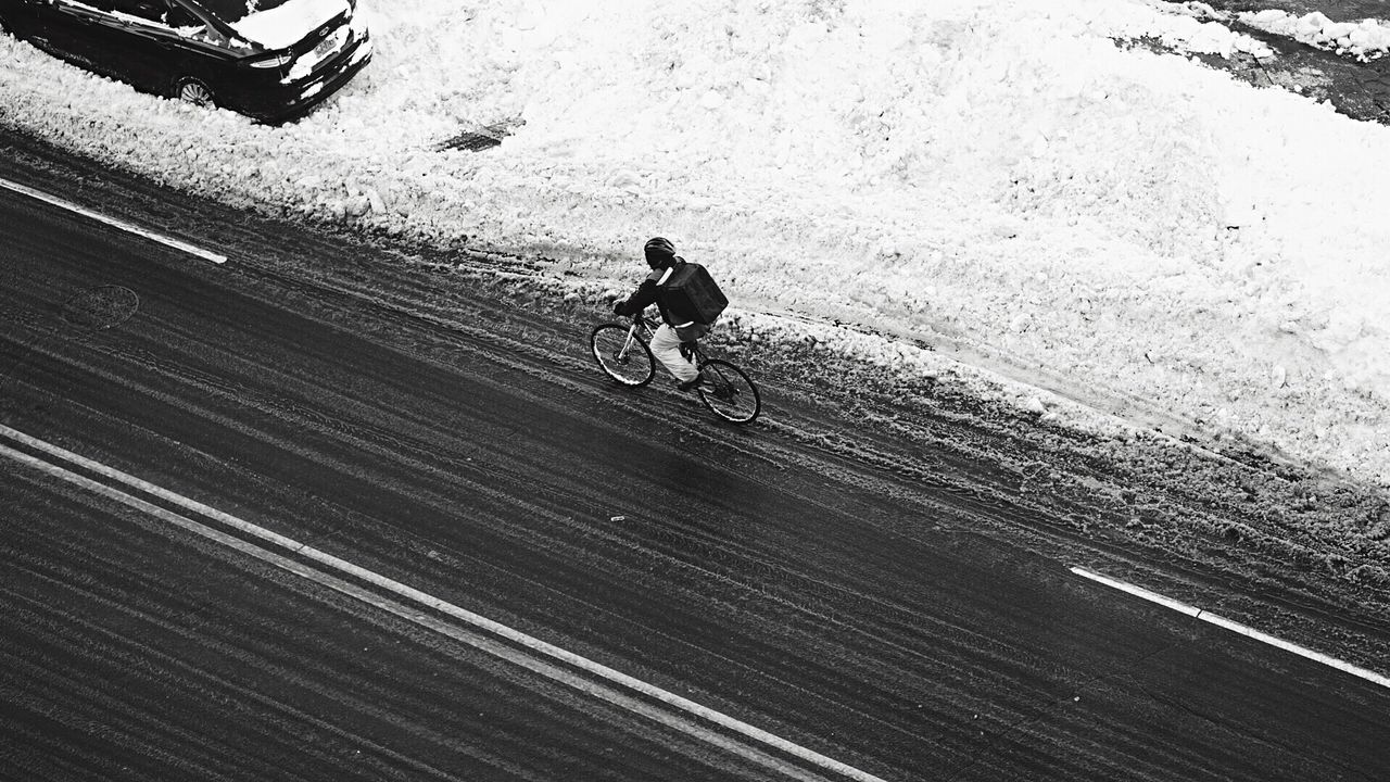 High angle view of person riding bicycle on street by snow