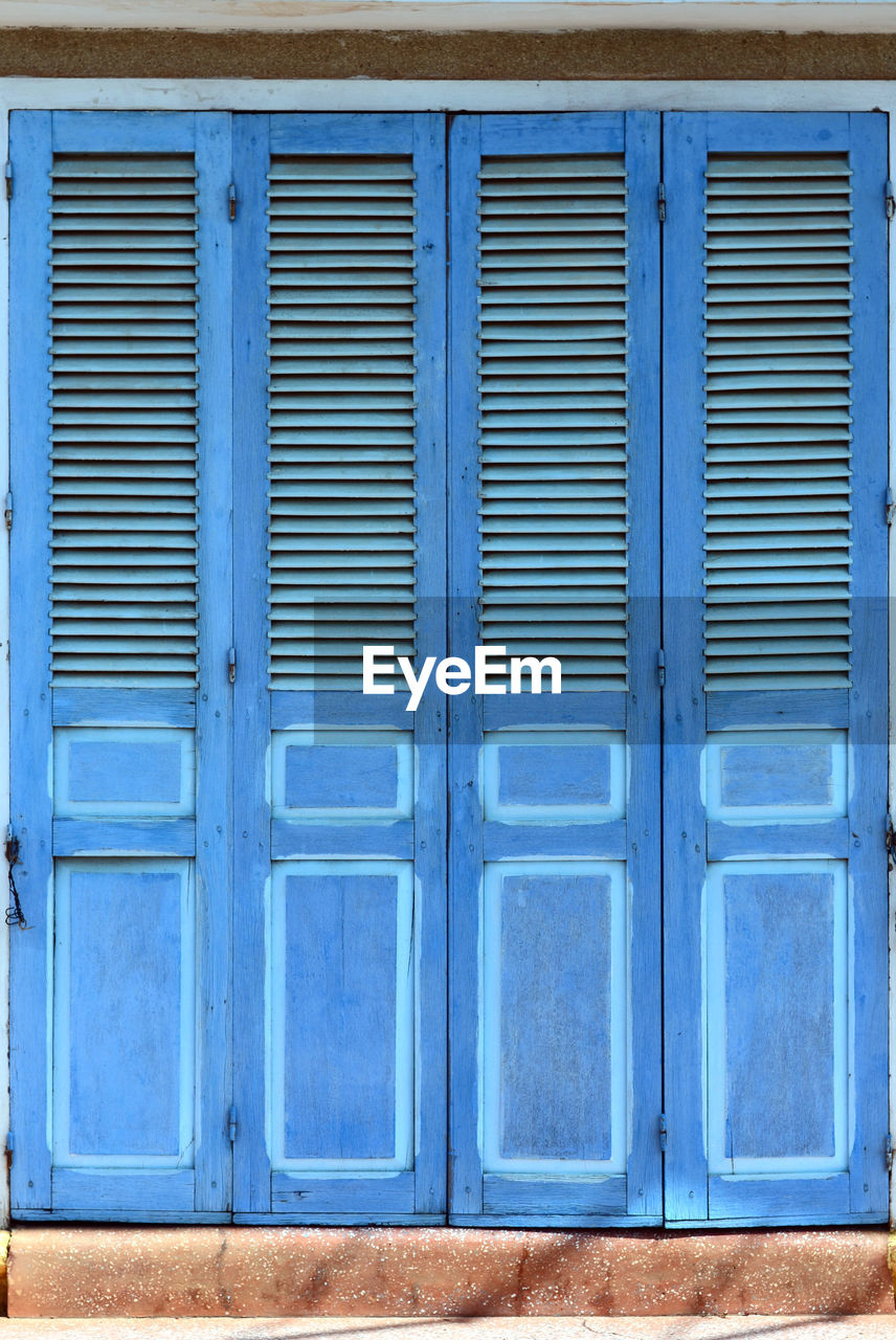 CLOSE-UP OF CLOSED SHUTTER OF BLUE BUILDING