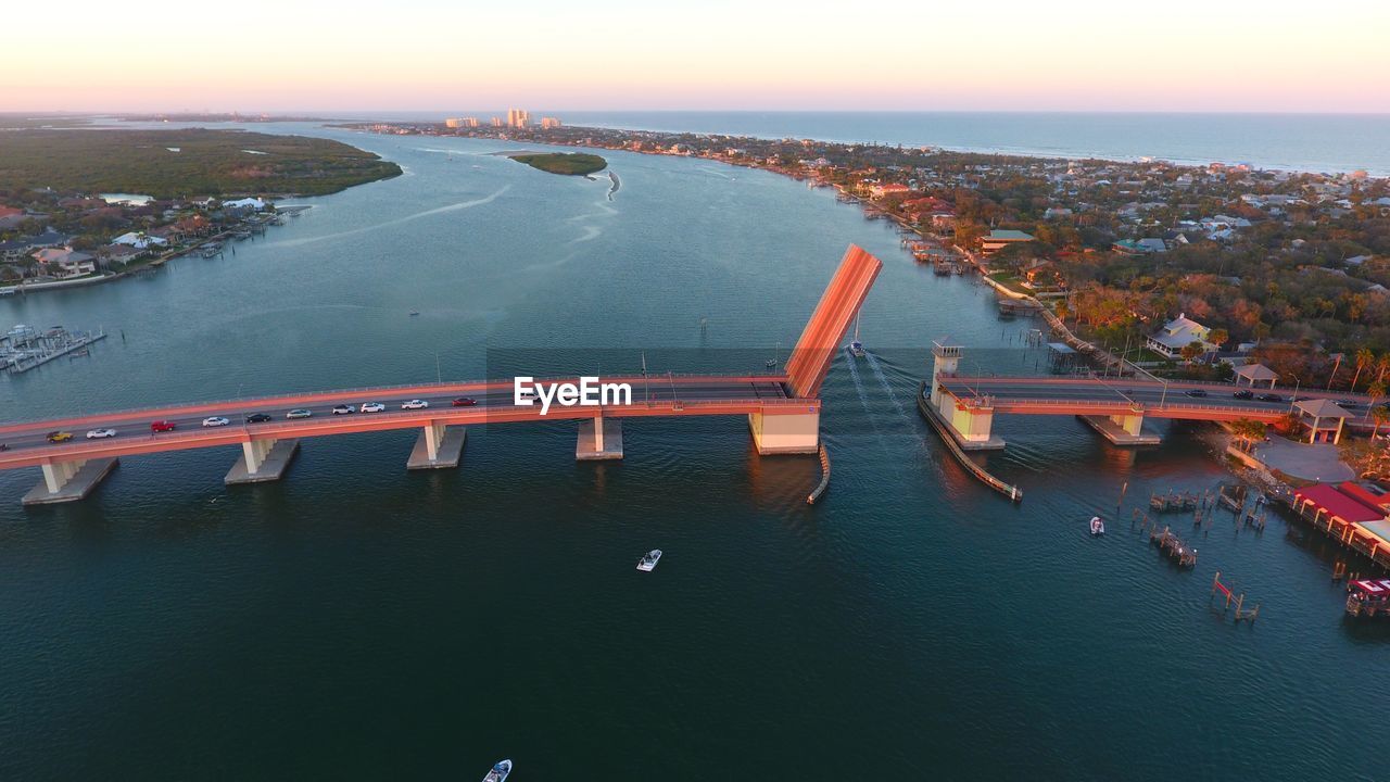 High angle view of illuminated bridge over river in city at sunset