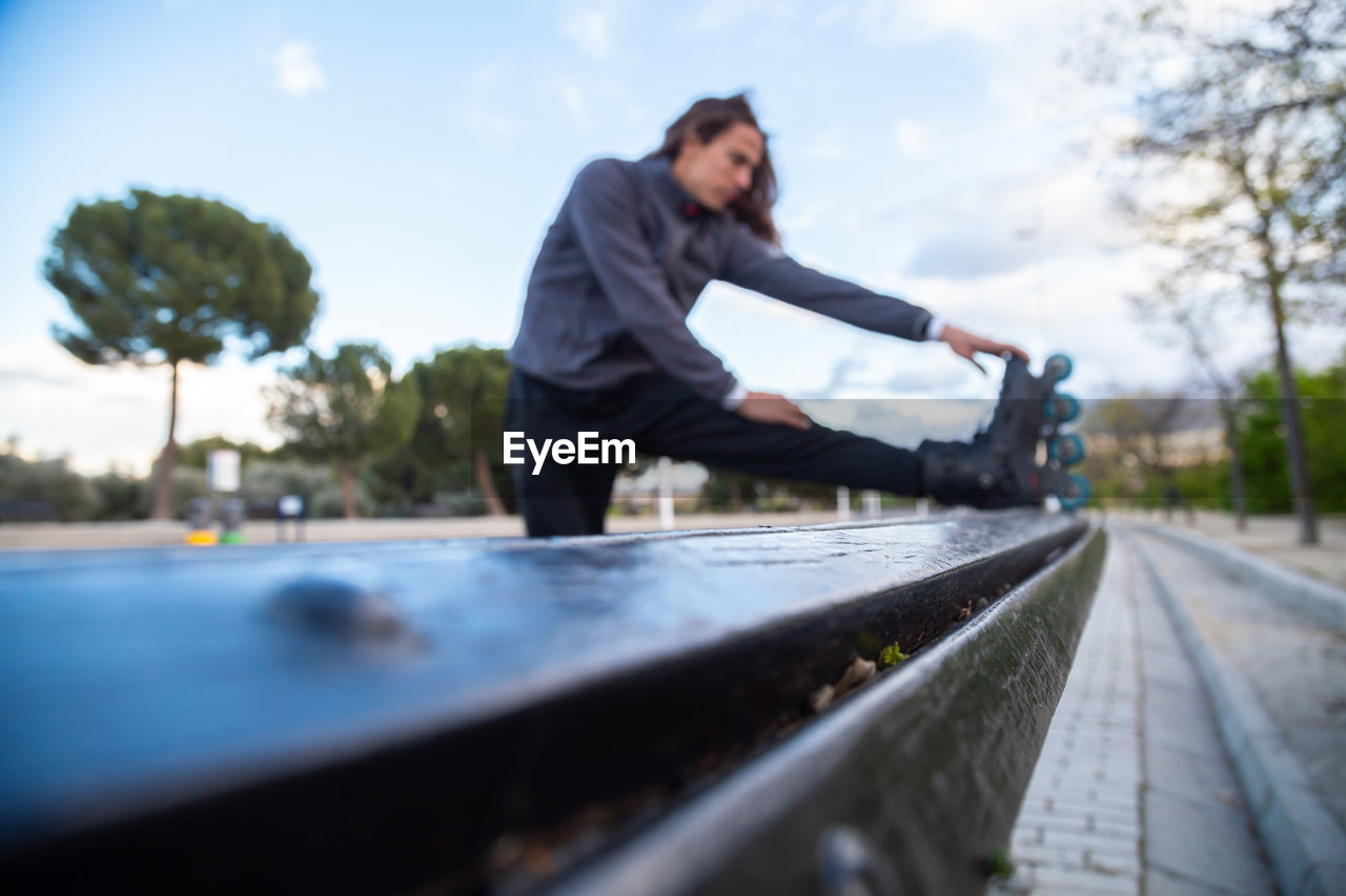 SIDE VIEW OF MAN ON RAILROAD TRACKS AGAINST SKY