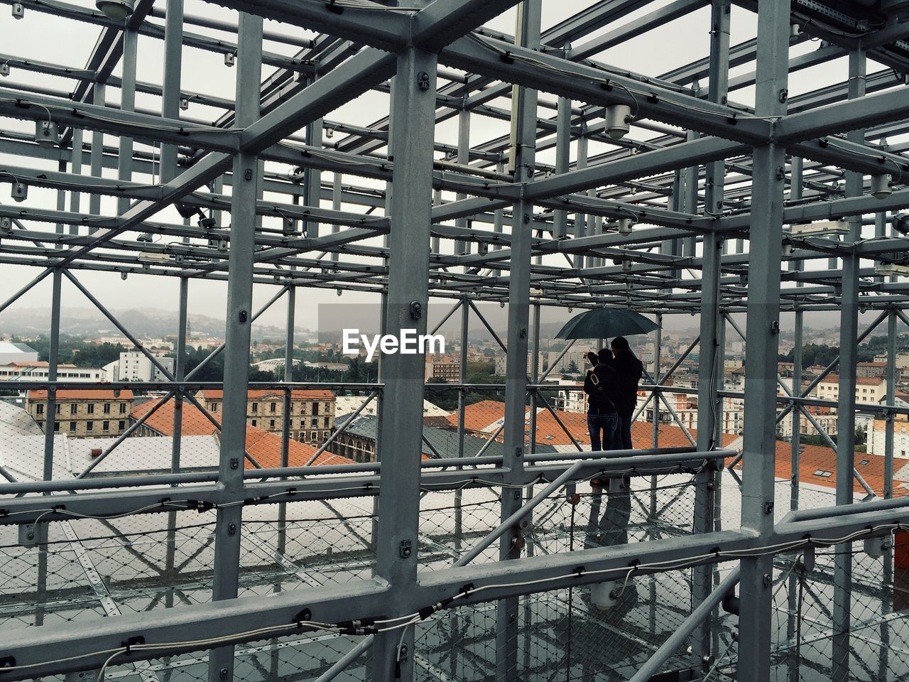 Rear view of people standing at incomplete building during rainy season