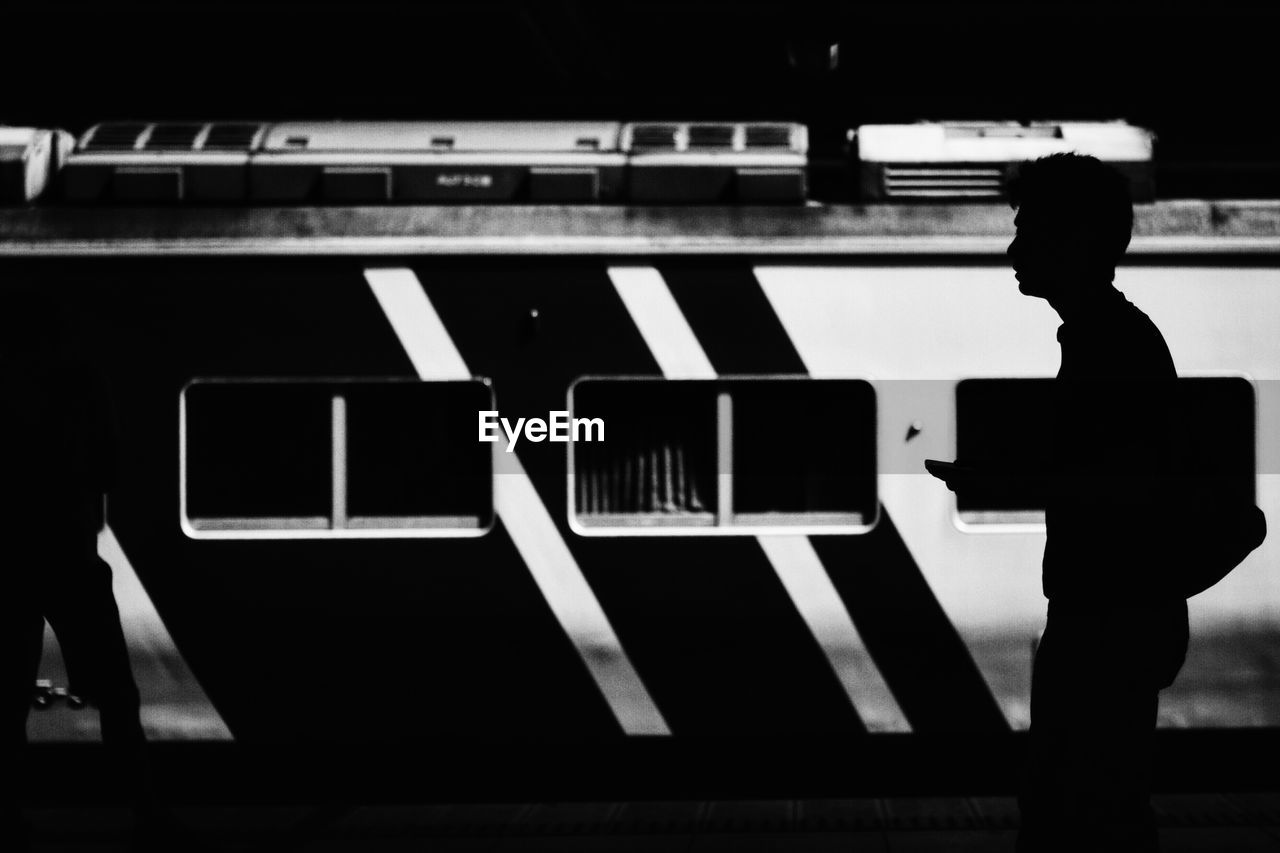 Man walking against train on railroad station