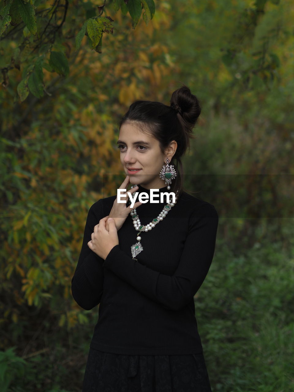 Young woman standing against trees