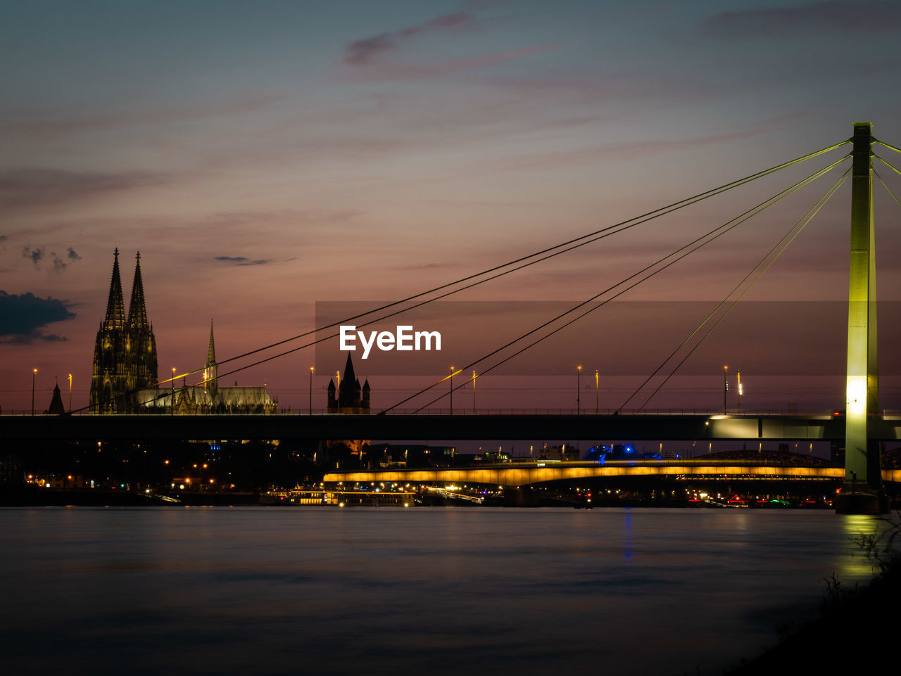 Illuminated bridge over river against sky at night