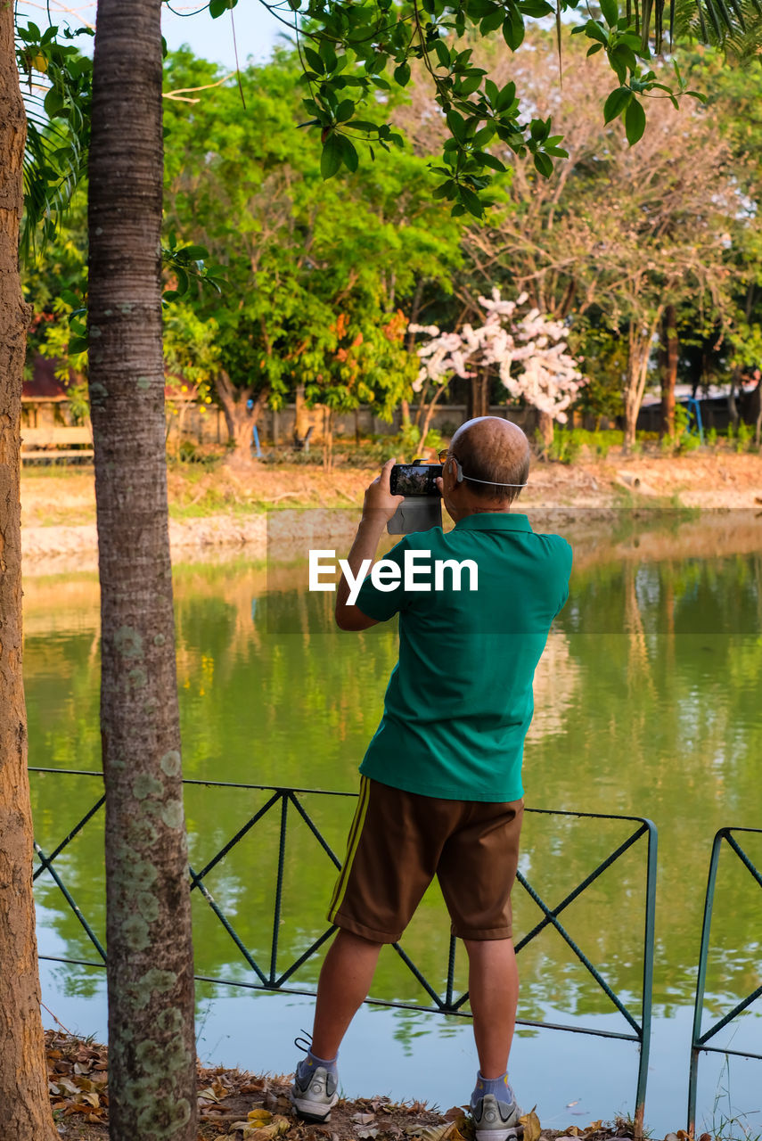 Rear view of man photographing lake