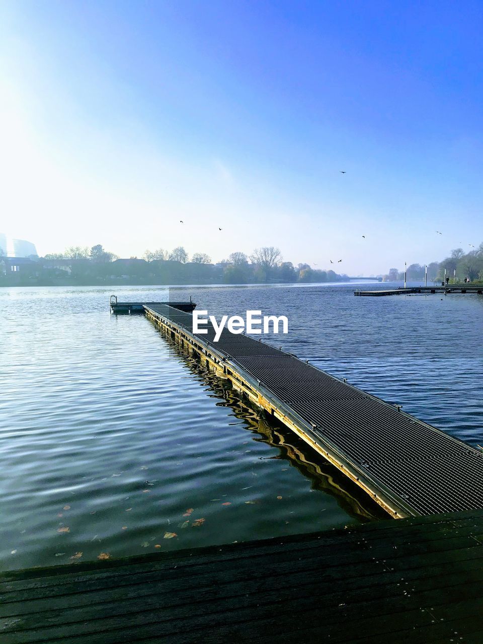 Pier over lake against clear blue sky