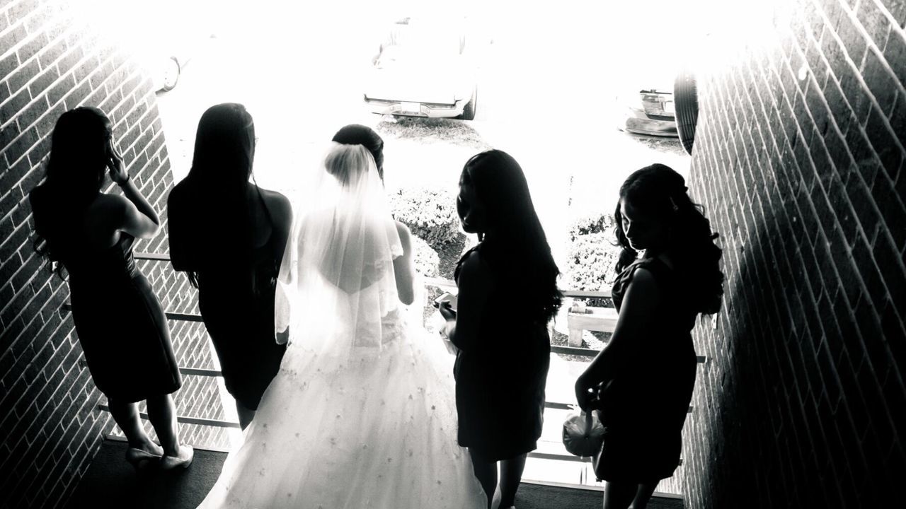 Rear view of bride with friends standing at balcony