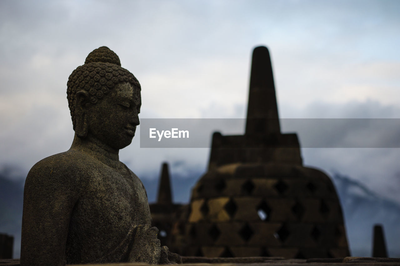 LOW ANGLE VIEW OF STATUE AGAINST TEMPLE