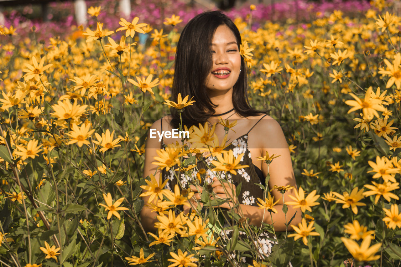 Smiling young woman by yellow flowering plants