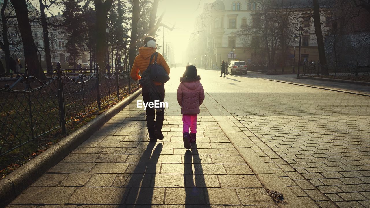 REAR VIEW OF PEOPLE WALKING ON ROAD