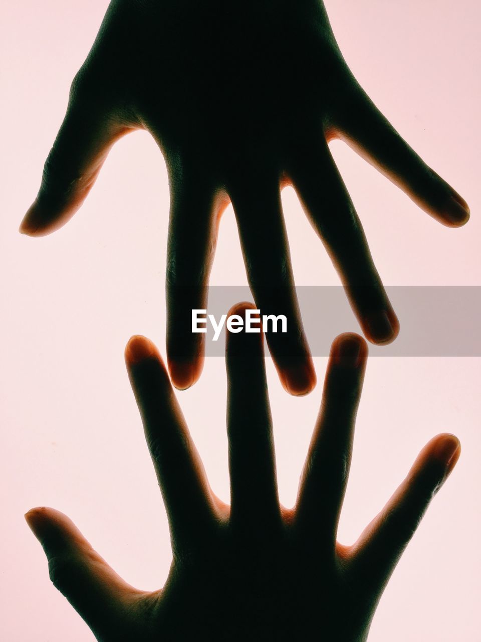 Cropped image of hands against illuminated white background