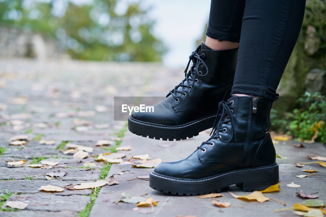 Close-up of the boots worn by a woman in military style in black with a stone floor background