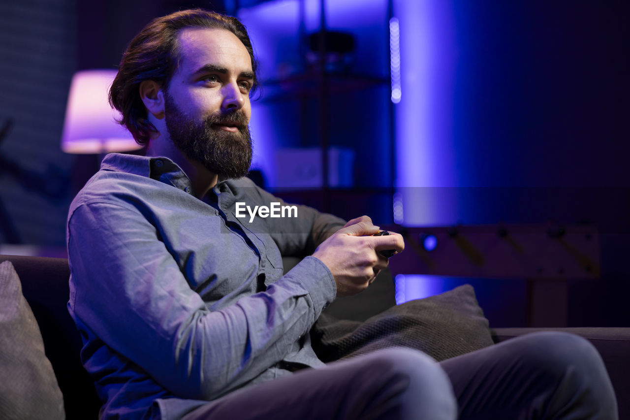 portrait of young man using mobile phone while sitting at home