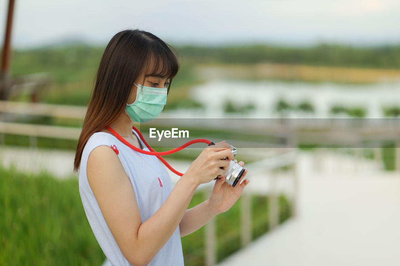 YOUNG WOMAN PHOTOGRAPHING WITH MOBILE PHONE