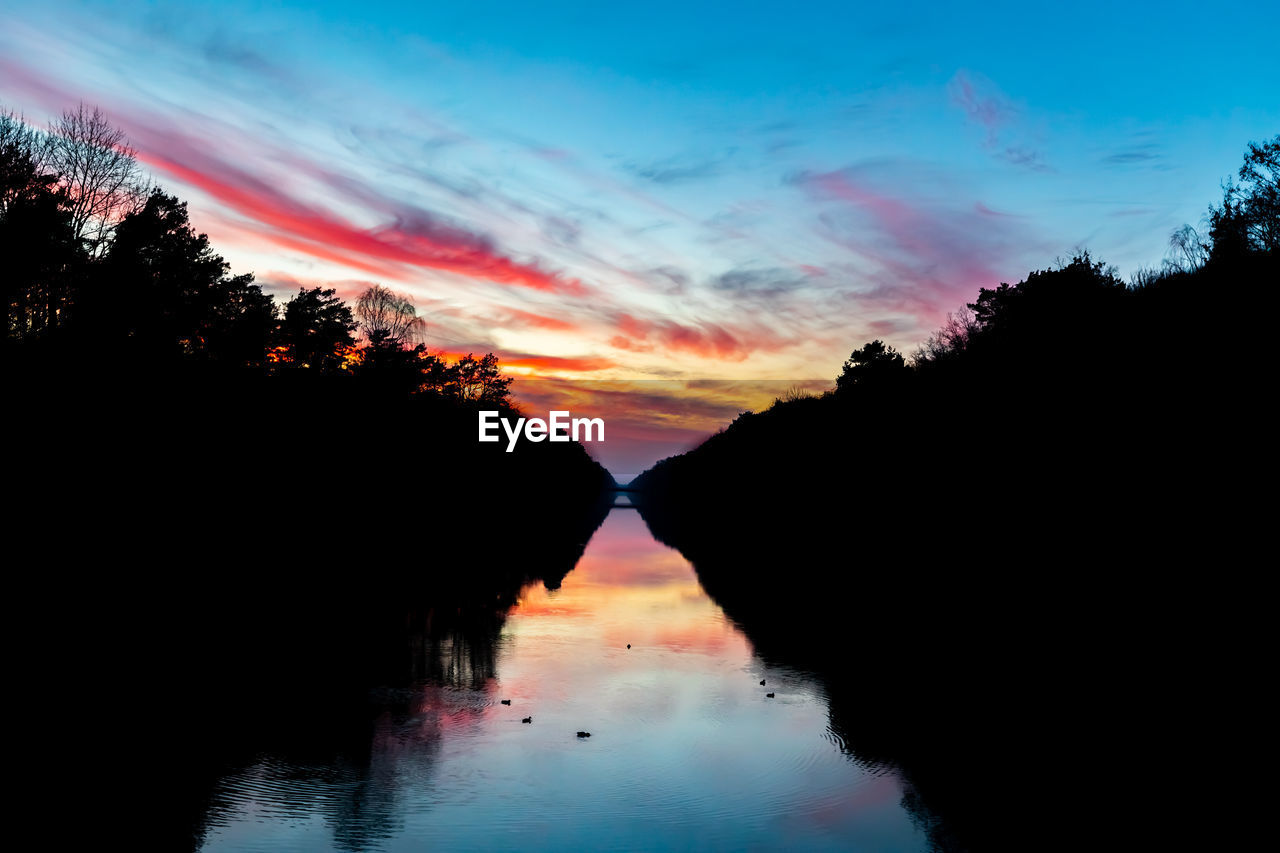 SCENIC VIEW OF LAKE AGAINST SKY AT SUNSET