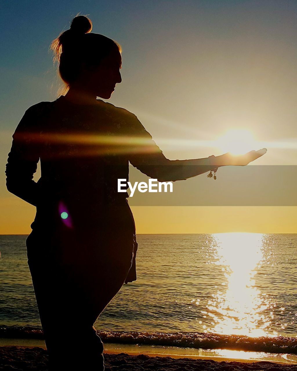 SILHOUETTE WOMAN STANDING AT BEACH DURING SUNSET