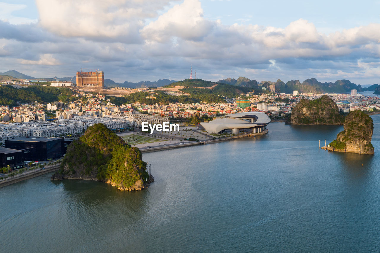 Aerial view of townscape by river against sky