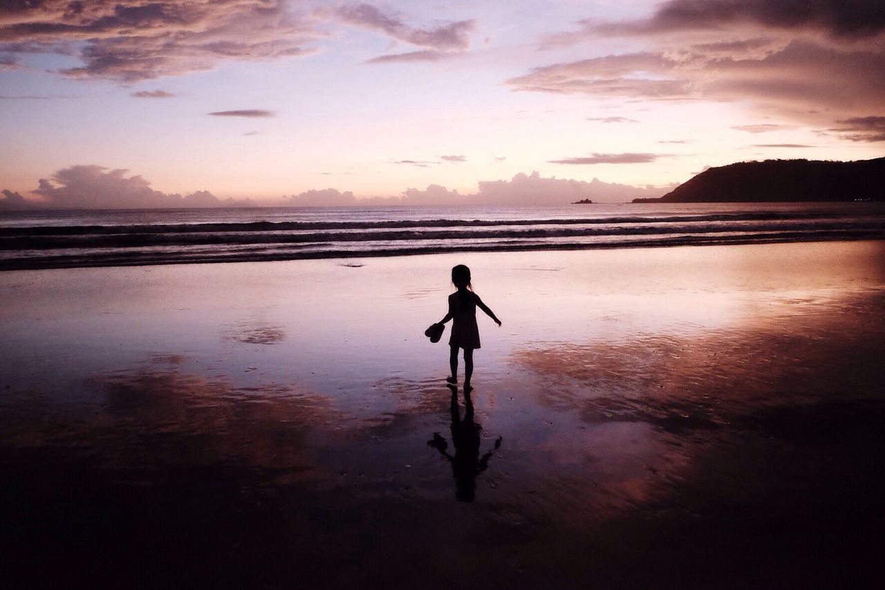Silhouette girl walking on shore at beach