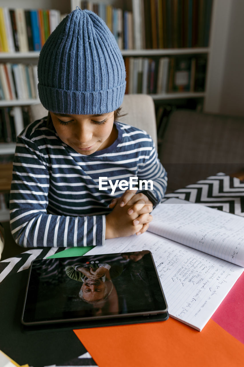 Boy communicating with teacher at homeschooling class in living room