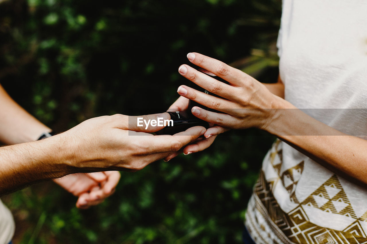 Cropped image of man giving ring to woman