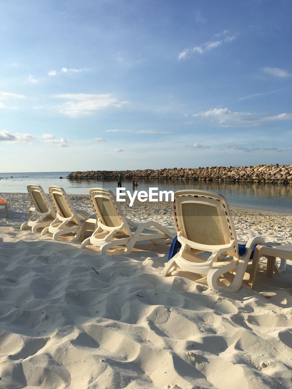 Deck chairs on beach against sky