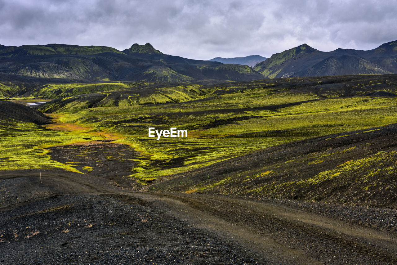 Scenic view of road by mountains against sky