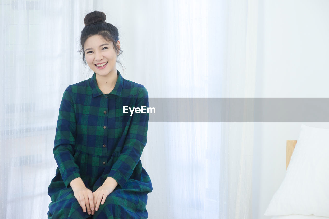 Portrait of smiling young woman sitting at home 