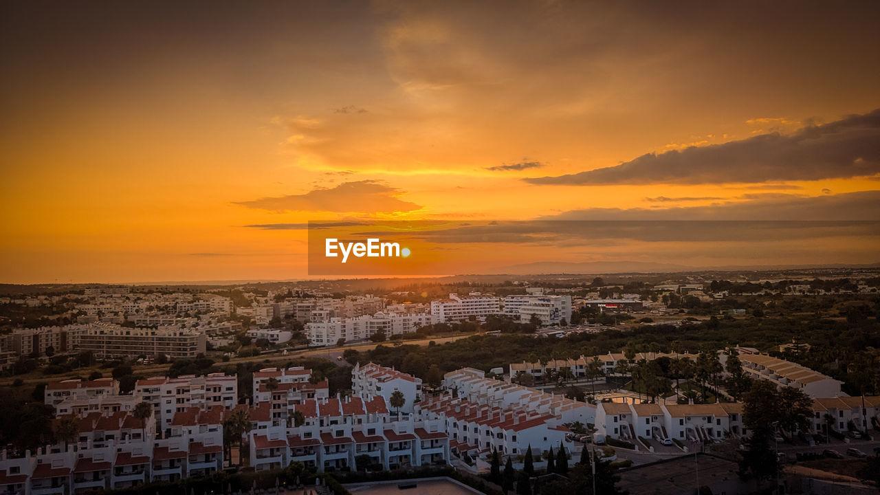 high angle view of townscape against cloudy sky during sunset