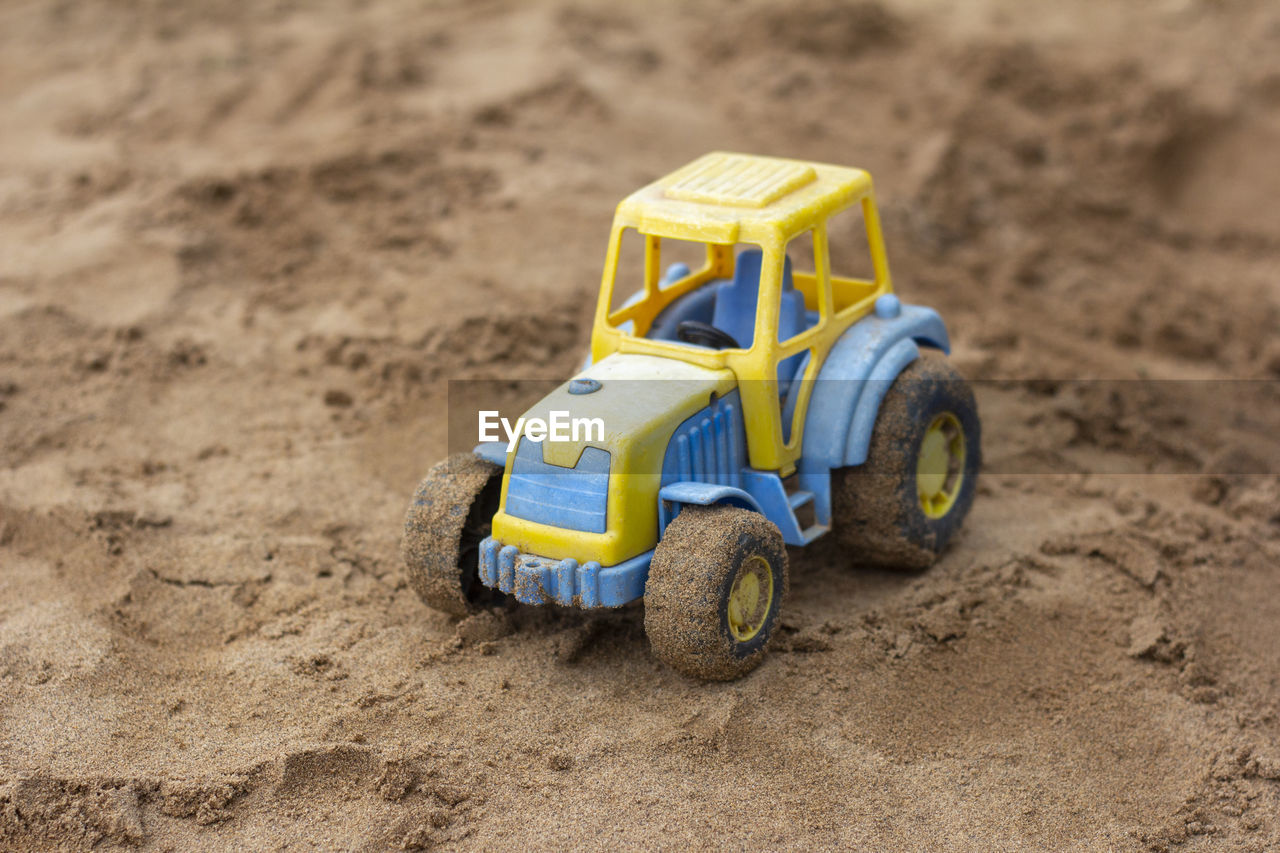 Children's toy tractor on the sandbox.a forgotten toy.