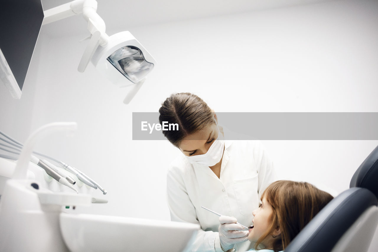 Female dentist examining girl at clinic