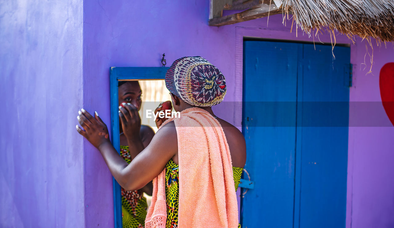 African woman doing her makeup outdoors in front of a mirror in the tropical part of ghana