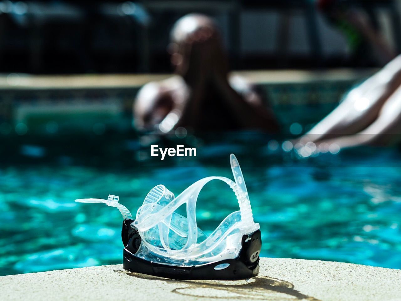Close-up of swimming goggles against man in pool
