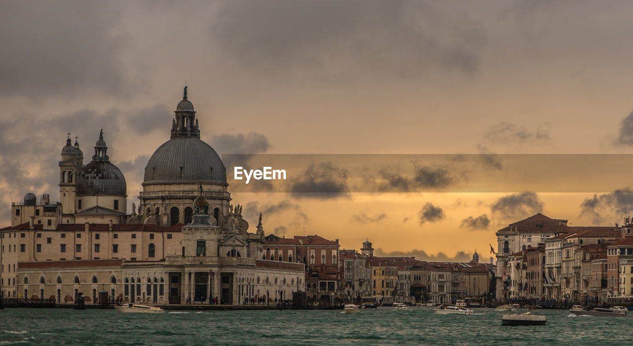 Grand canal amidst santa maria della salute and building against cloudy sky