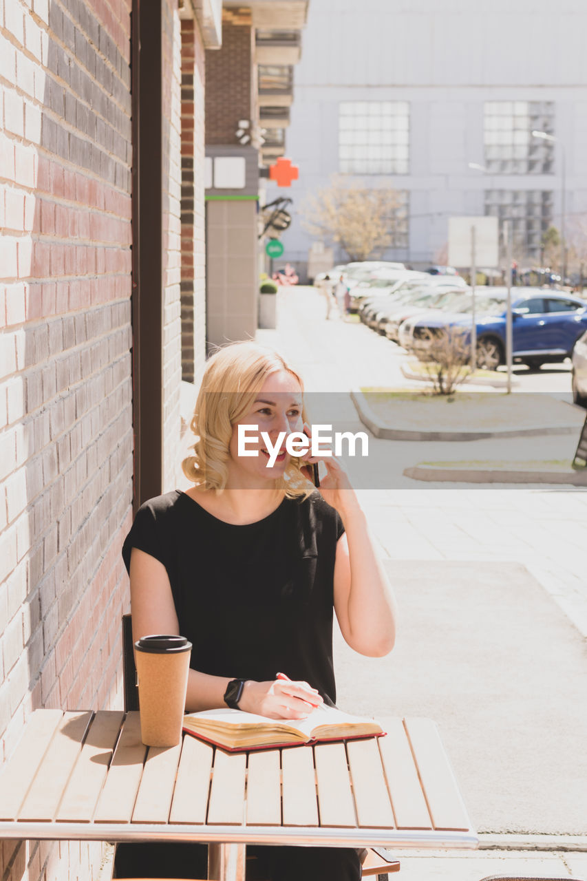 portrait of young woman using mobile phone while sitting at table