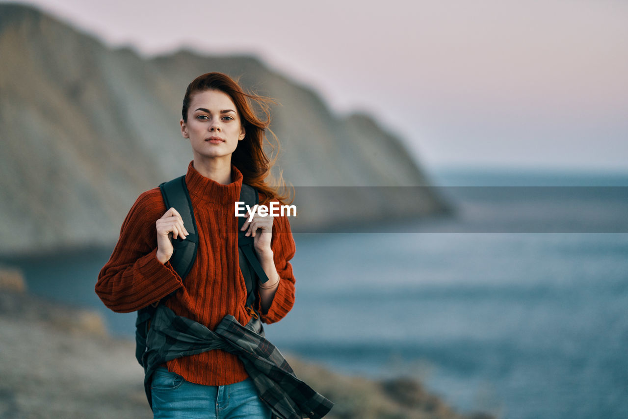 PORTRAIT OF WOMAN STANDING AGAINST SEA