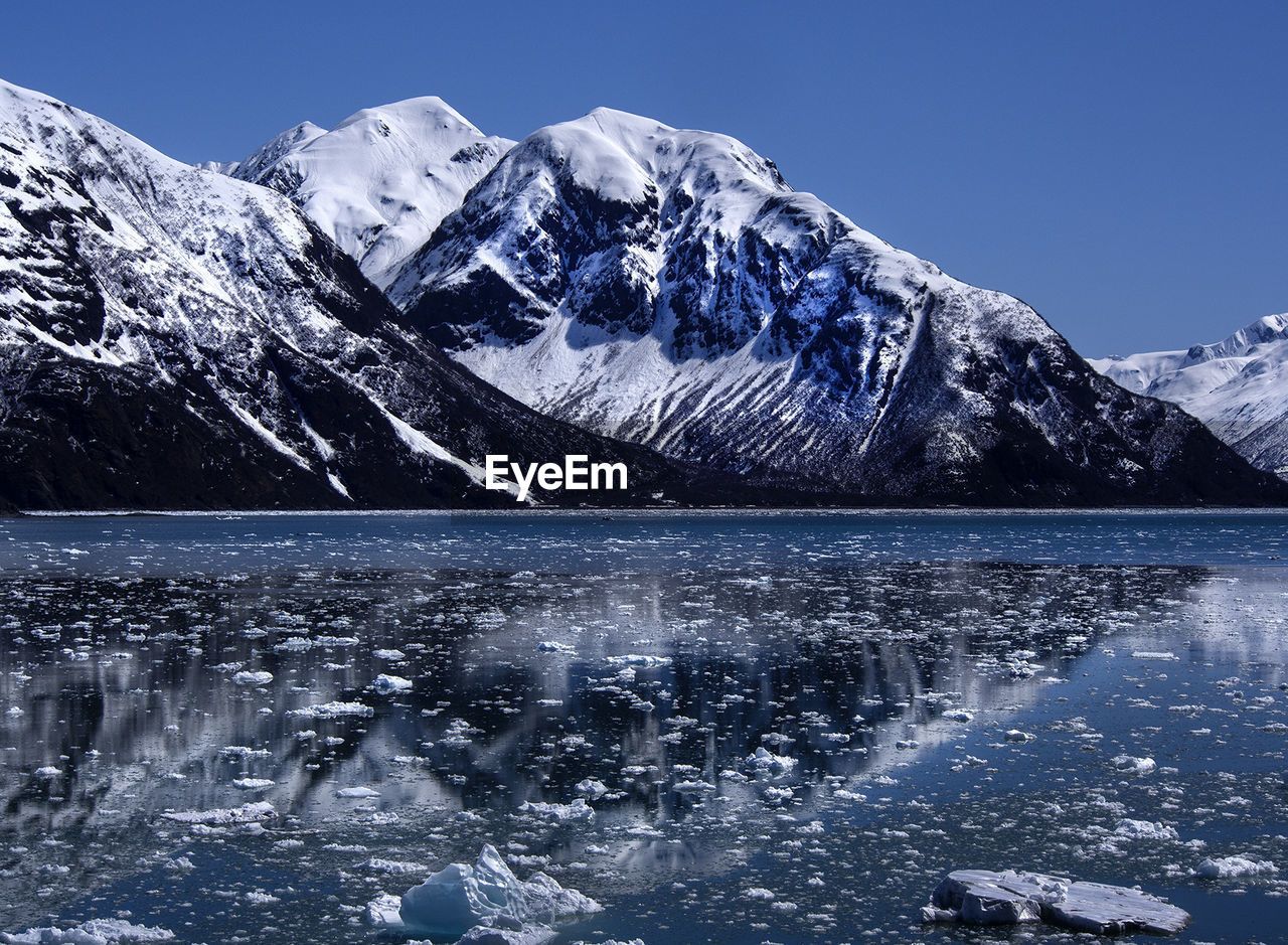 Snow floating on river by snowcapped mountain