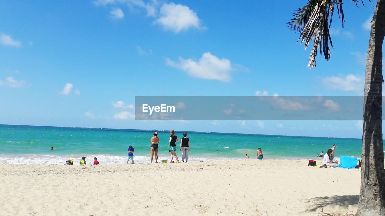 People on beach against blue sky