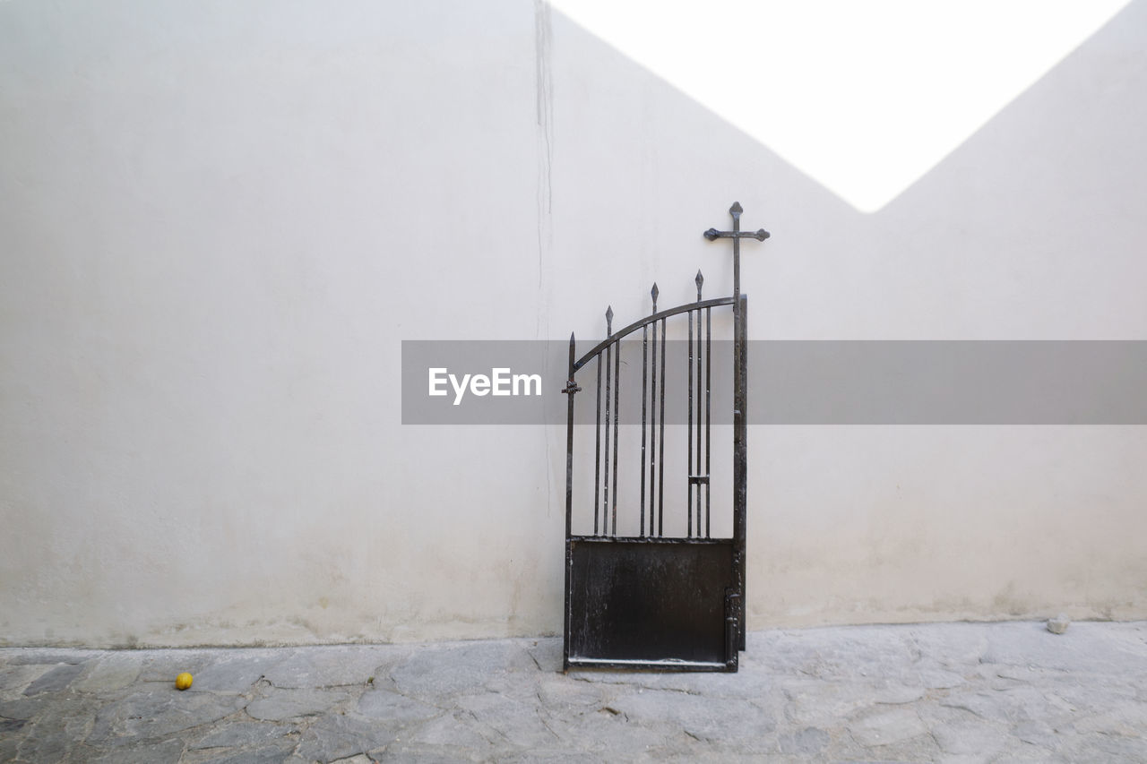 Black gate against wall in a greek orthodox churchyard 
