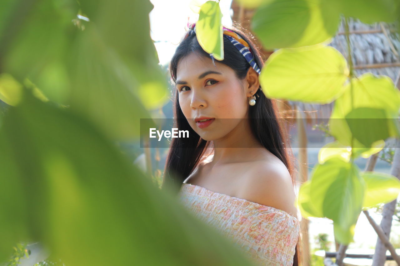 Portrait of young woman looking away while standing on leaves