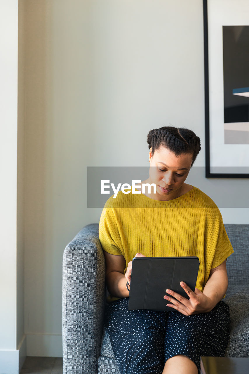 Businesswoman using graphics tablet while sitting on sofa at office