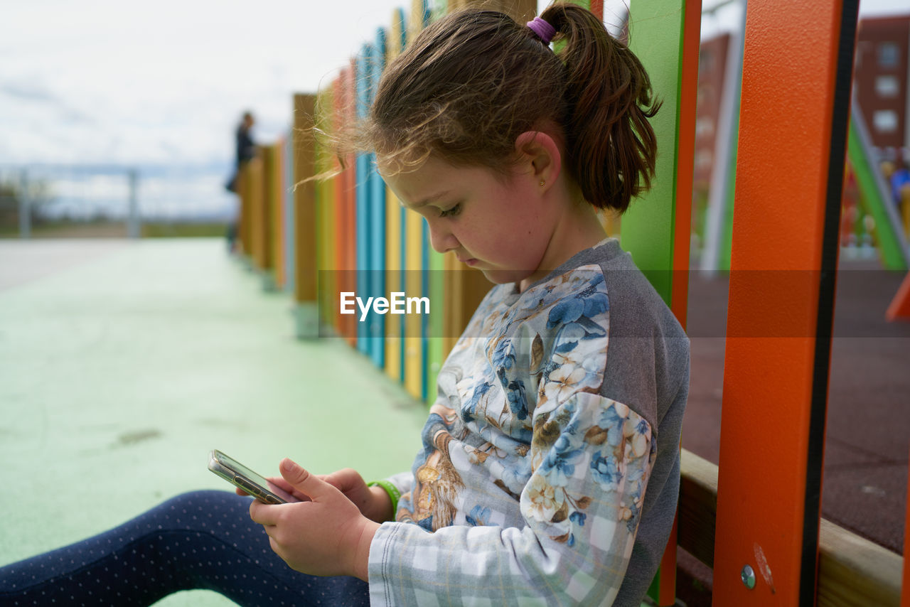 Little girl using smartphone on playground