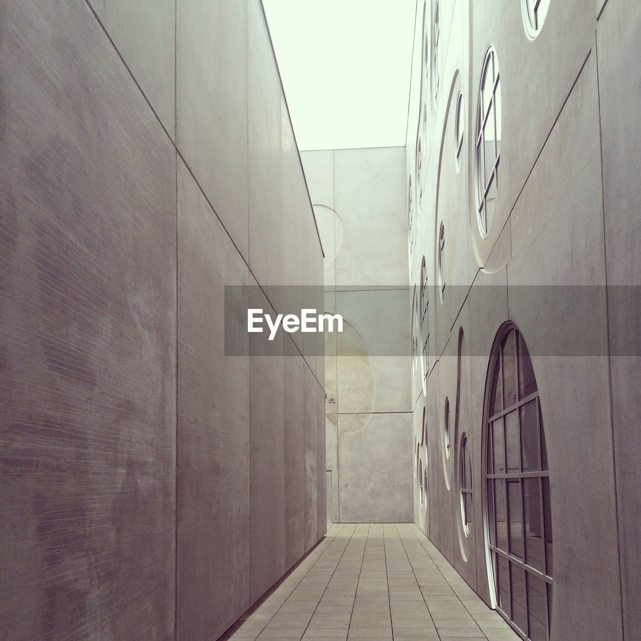 Corridor amidst modern buildings against sky