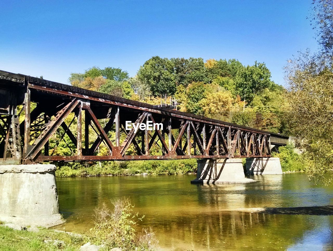 Low angle view of bridge over river against trees