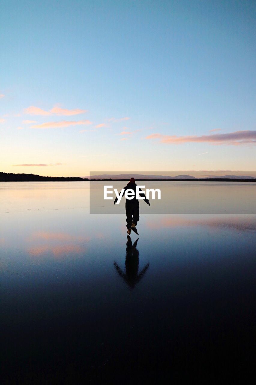 Man on lake against sky